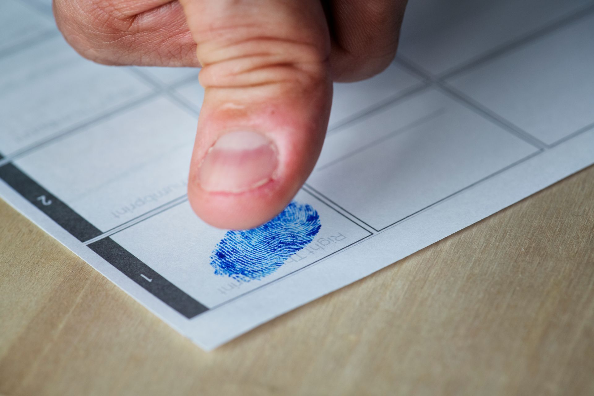 Thumb pressing blue fingerprint on a document form