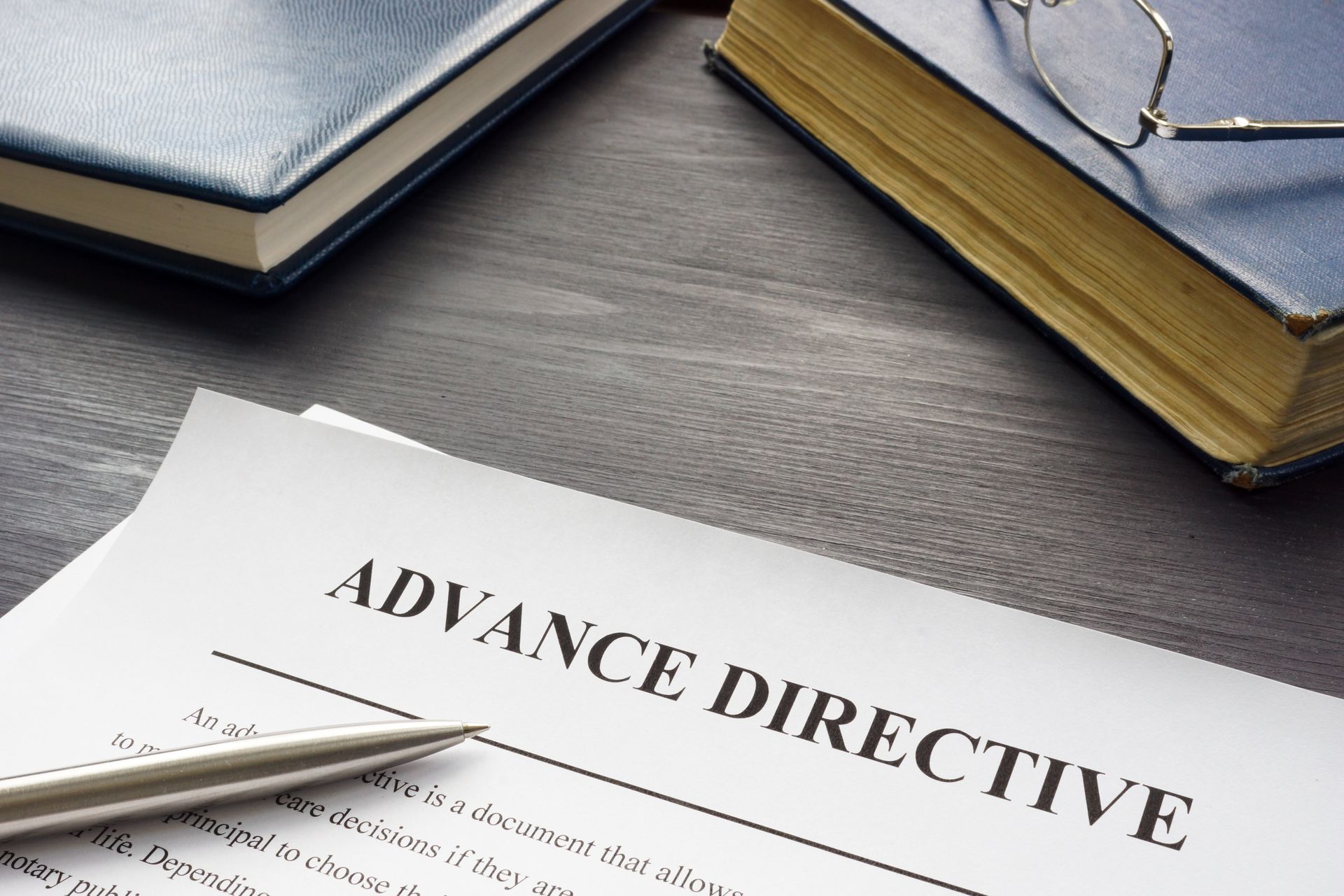 Hands signing a document on a clipboard at a desk with glasses nearby.