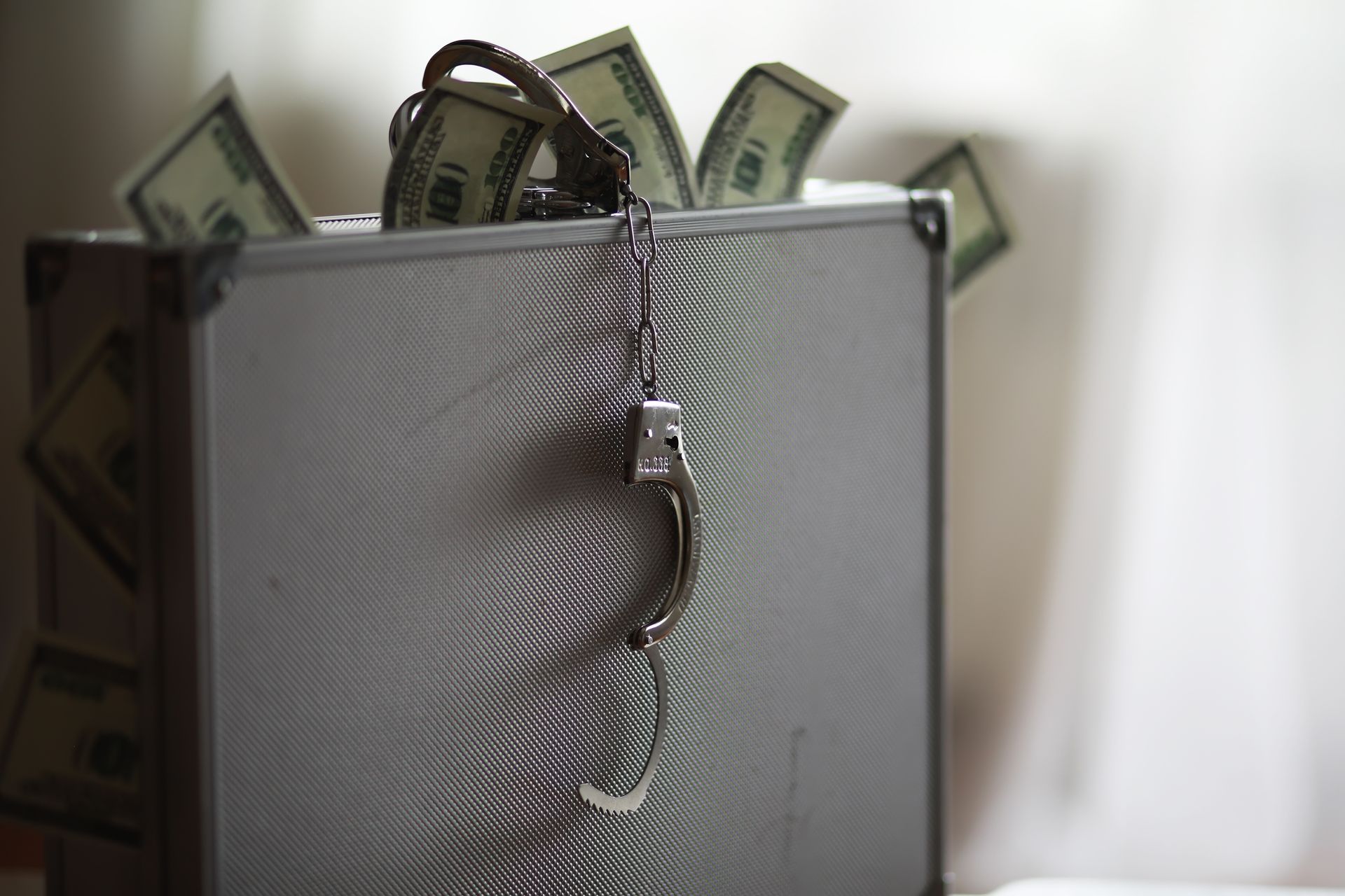 Close-up of a silver suitcase with cash and a chain draped over it