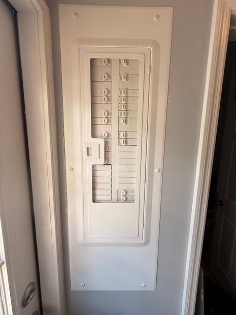 Electrical breaker panel with wiring and circuit breakers mounted on a gray board.