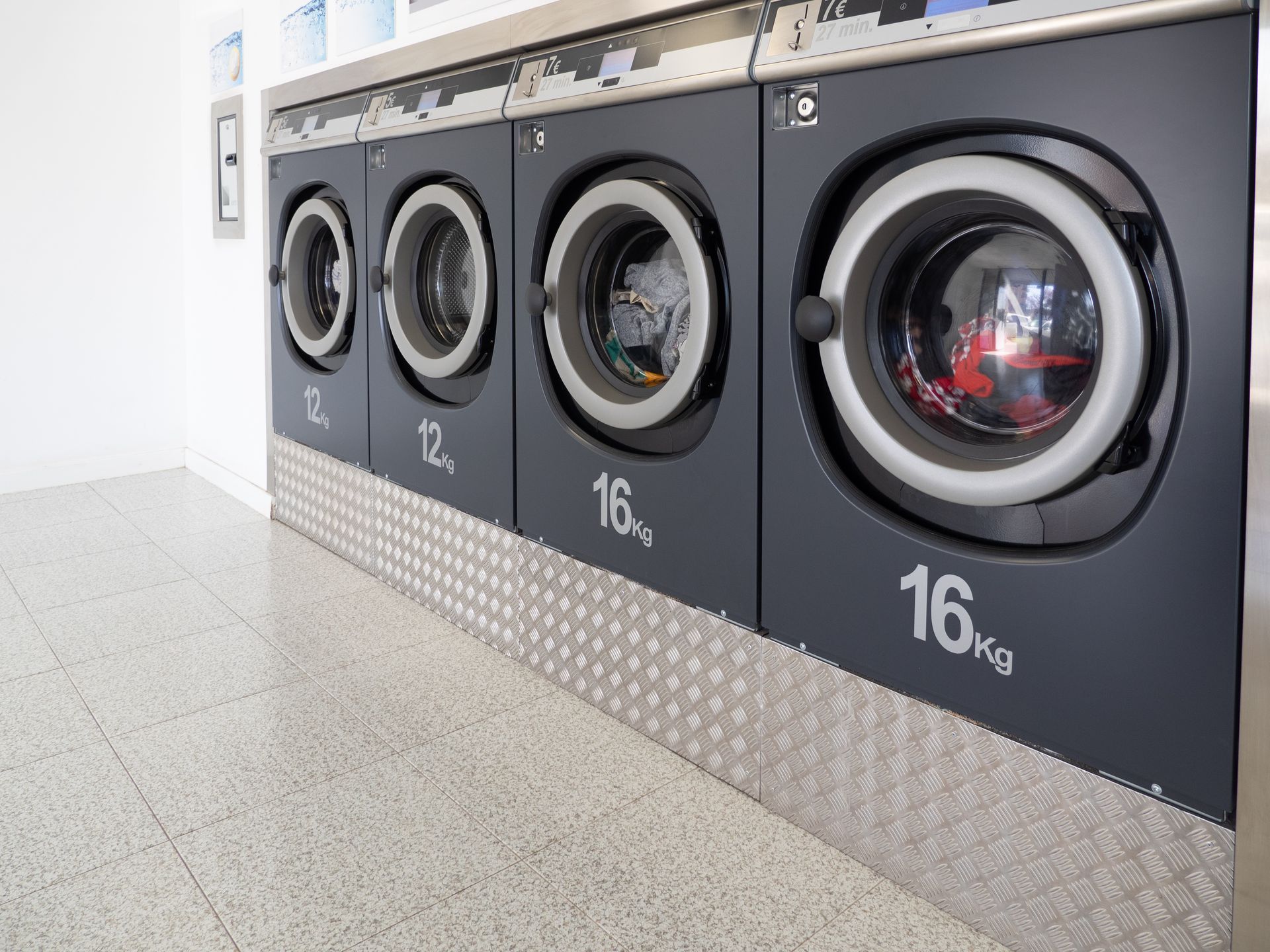 Several laundry machines are set up in a laundry area offering services for washing clothes.
