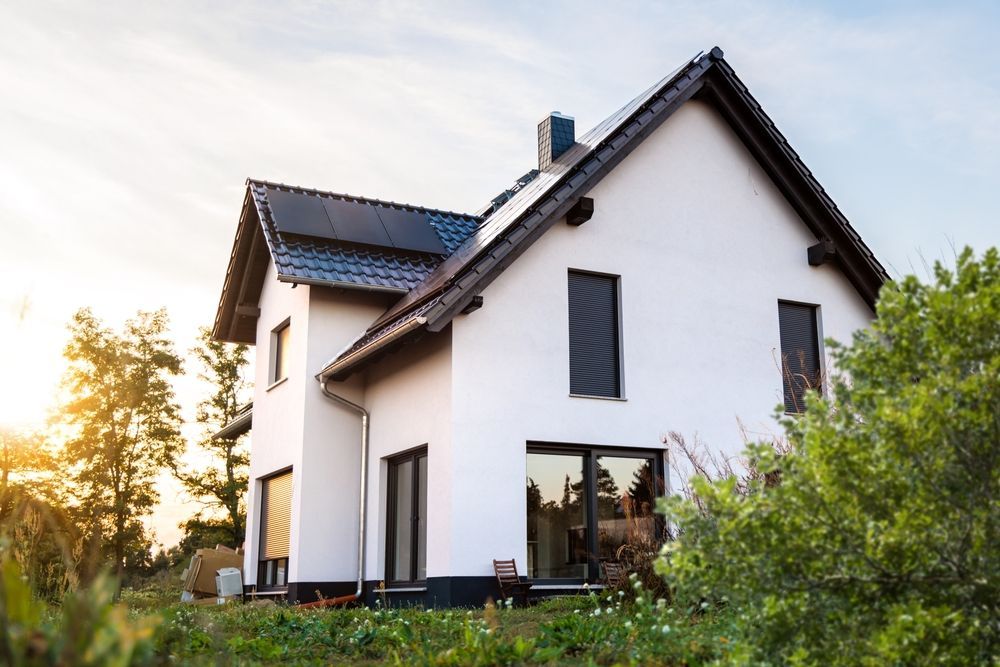 Modern white house with dark roof and large windows in a sunny grassy yard