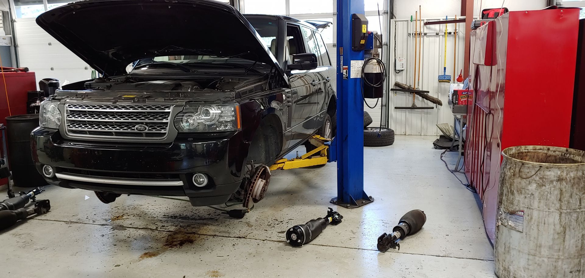 A black range rover is sitting on a lift in a garage. | Import Specialty Service