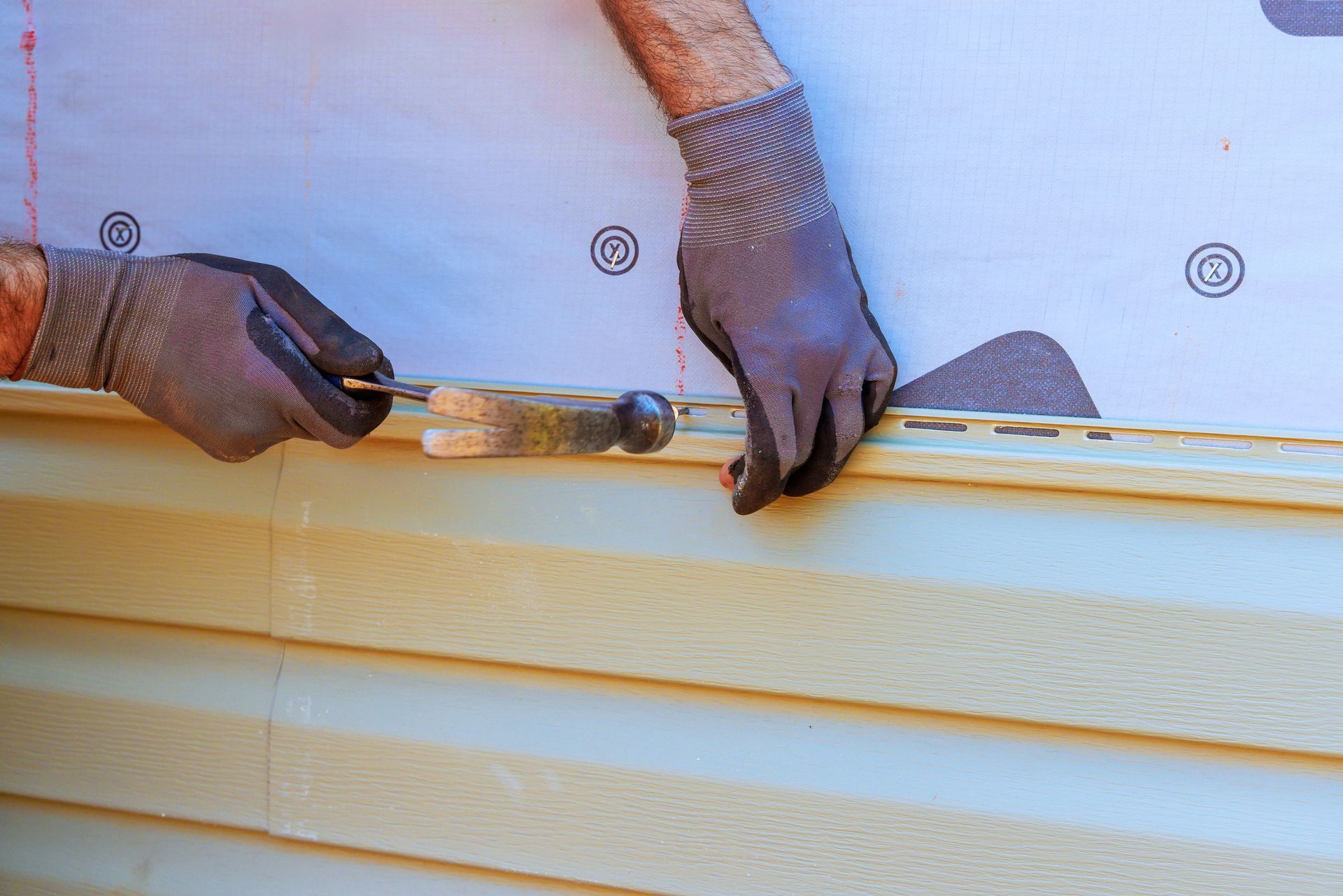 A man is installing siding on a house with a spatula.
