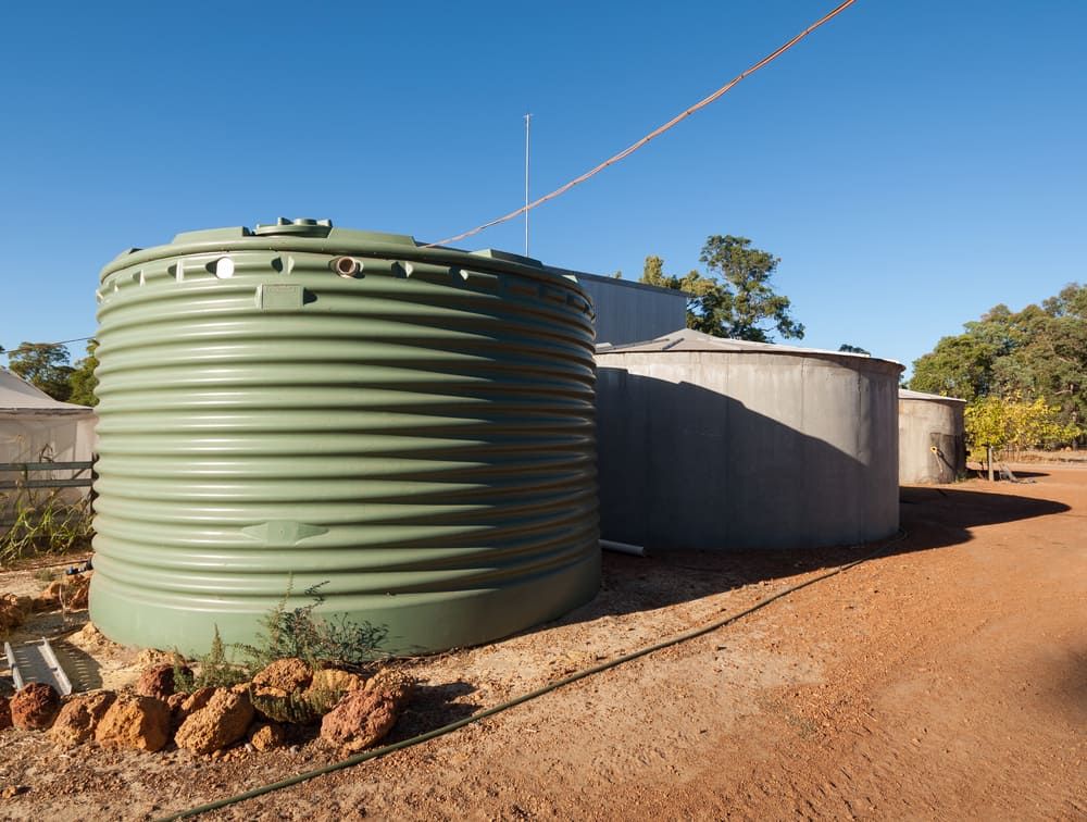 A Large Green Rainwater Tank and Several Grey Tanks — Hastings Water Care In Redbank, NSW