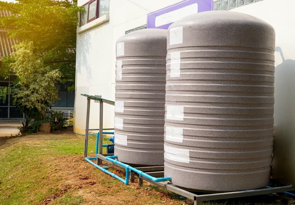 Two water tanks are sitting next to each other in front of a building — Hastings Water Care In Redbank, NSW