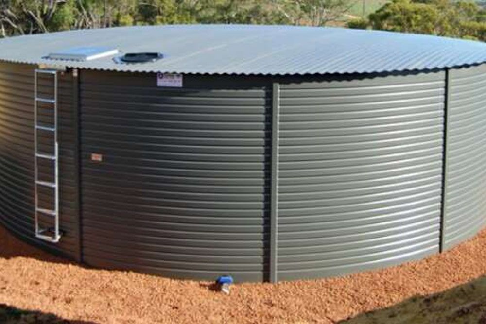 A large green water tank on brown dirt — Hastings Water Care In Redbank, NSW