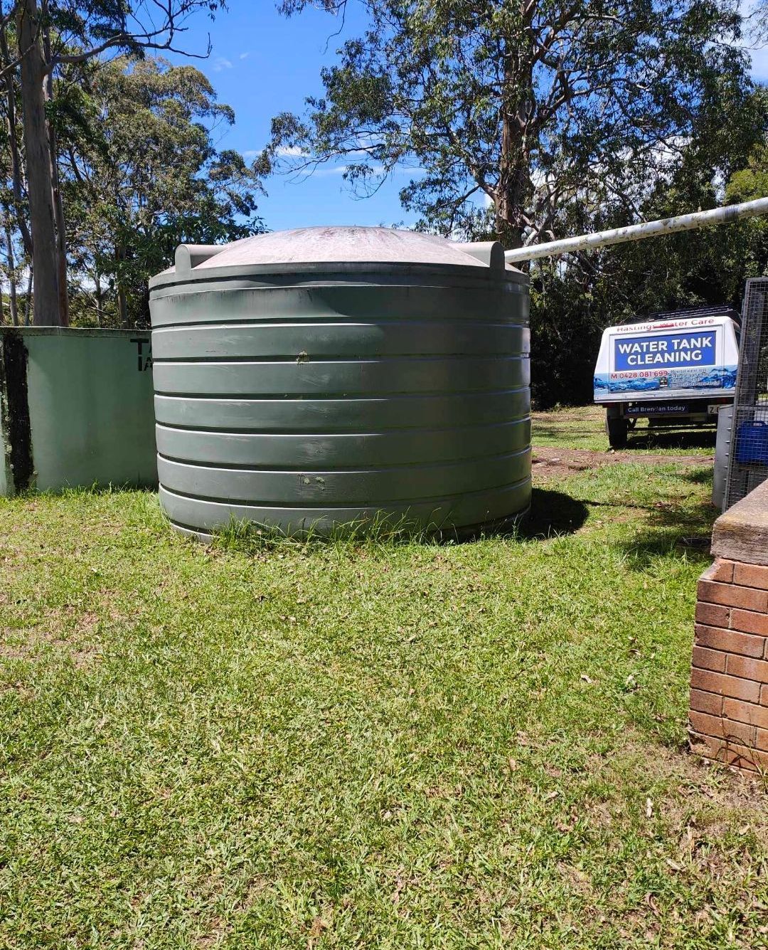 A green water tank in a grass backyard - Hastings Water Care in Port Macquarie NSW