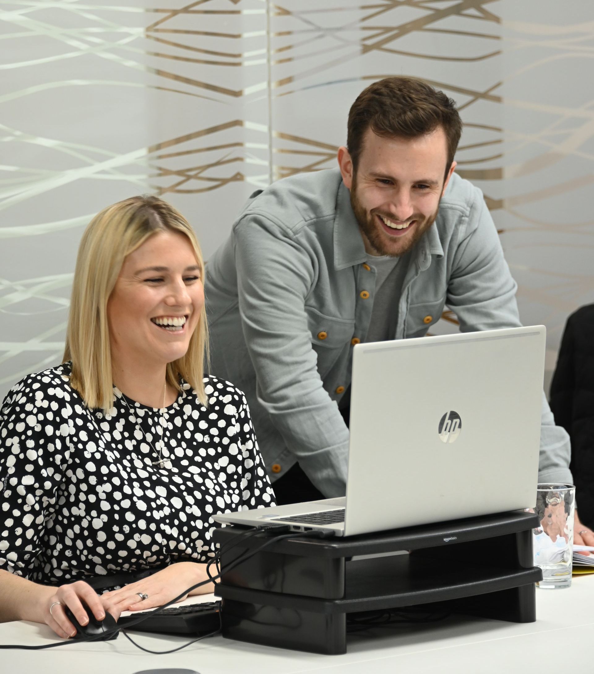 A man and a woman are looking at an hp laptop