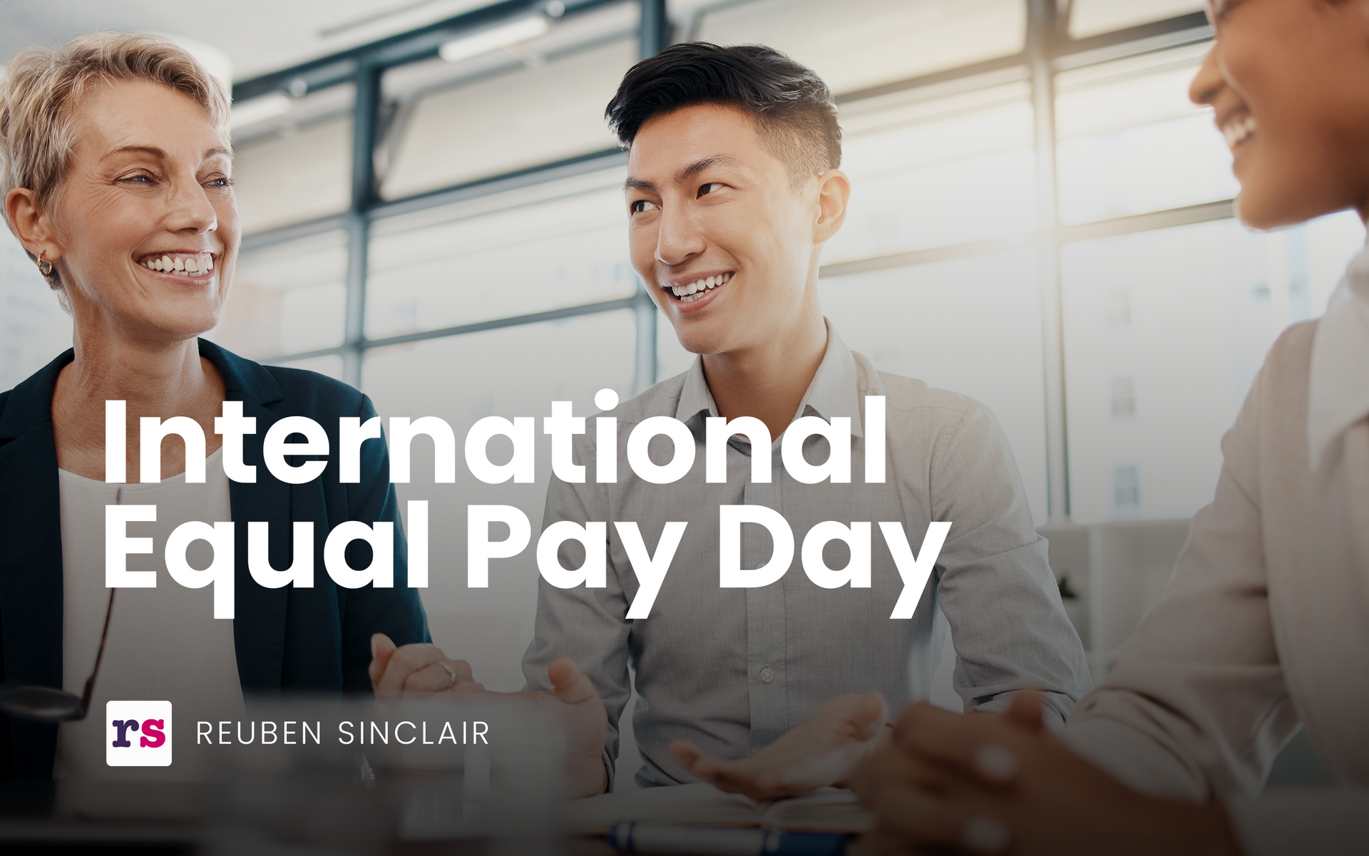 A group of people are sitting around a table and smiling for international equal pay day.