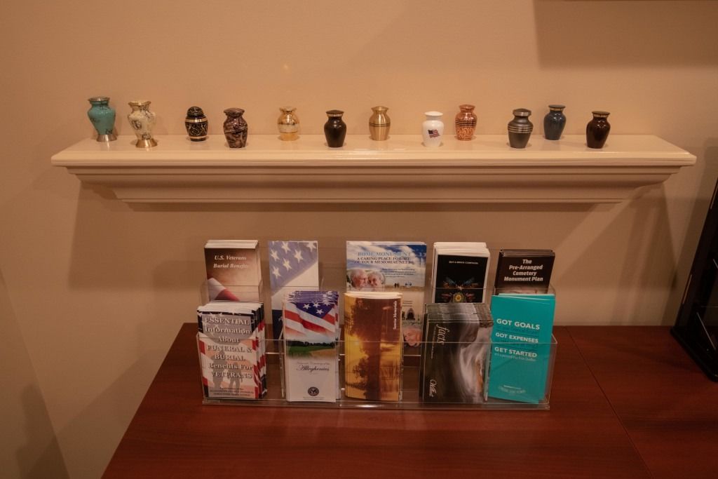 Small decorative figurines lined on a white shelf above assorted product boxes on a wooden table.
