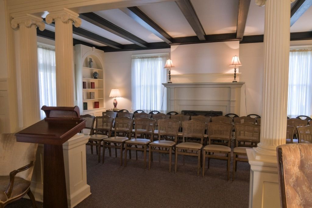 Empty meeting room with rows of chairs, white columns, and soft lighting
