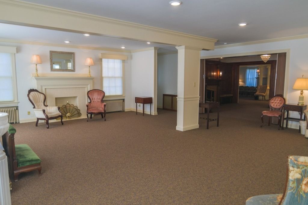 Empty carpeted lounge with chairs, windows, and recessed ceiling lights