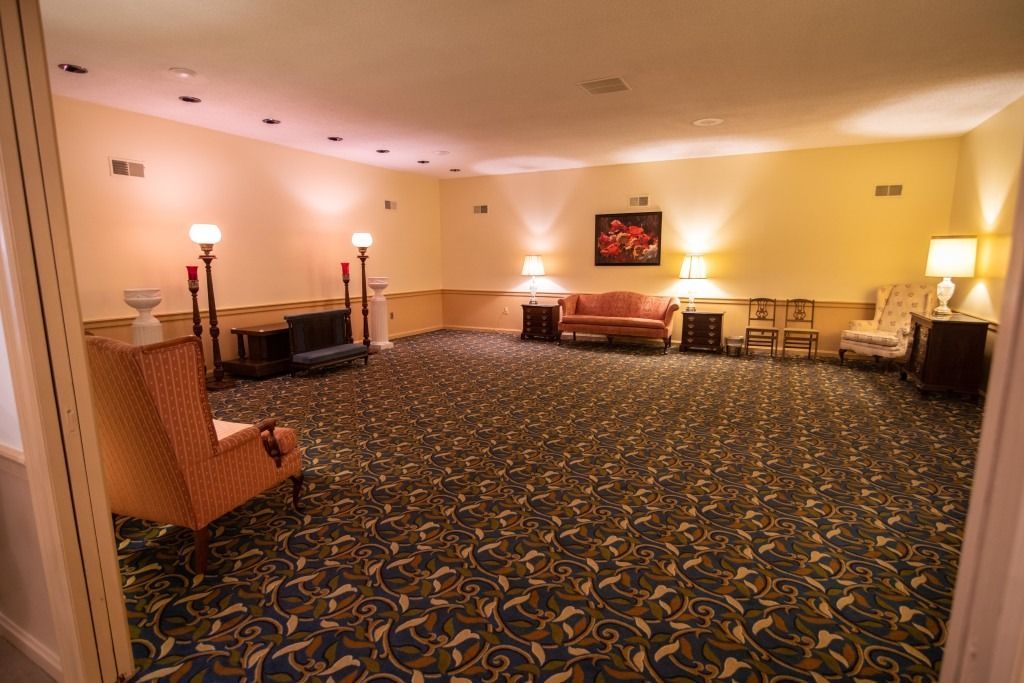Empty hotel conference room with patterned carpet, chairs along the walls, and warm lamps around the room