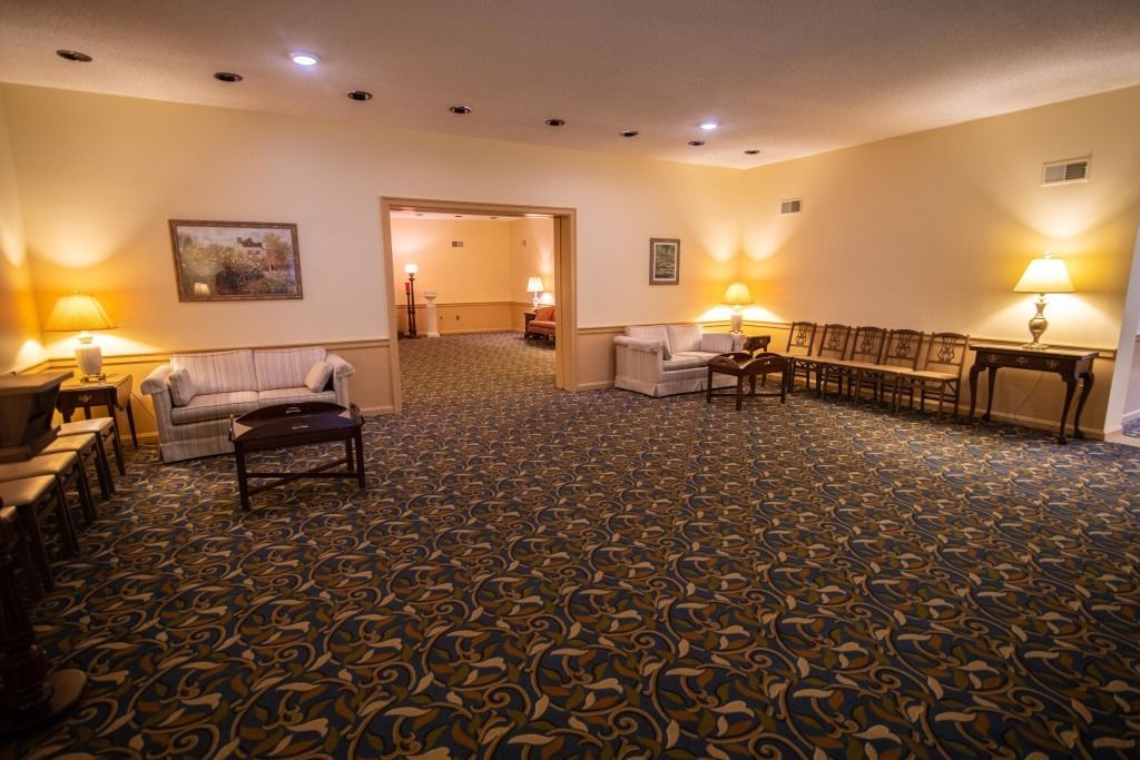 Empty carpeted hotel lounge with sofas, lamps, and warm lighting at night