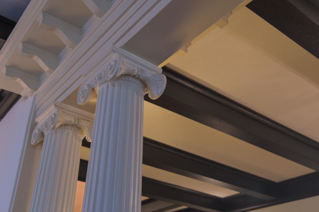 White decorative column supporting an ornate ceiling in a classical interior