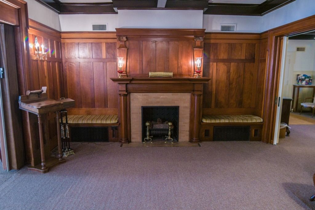 Wood-paneled room with a fireplace, built-in benches, and patterned carpet