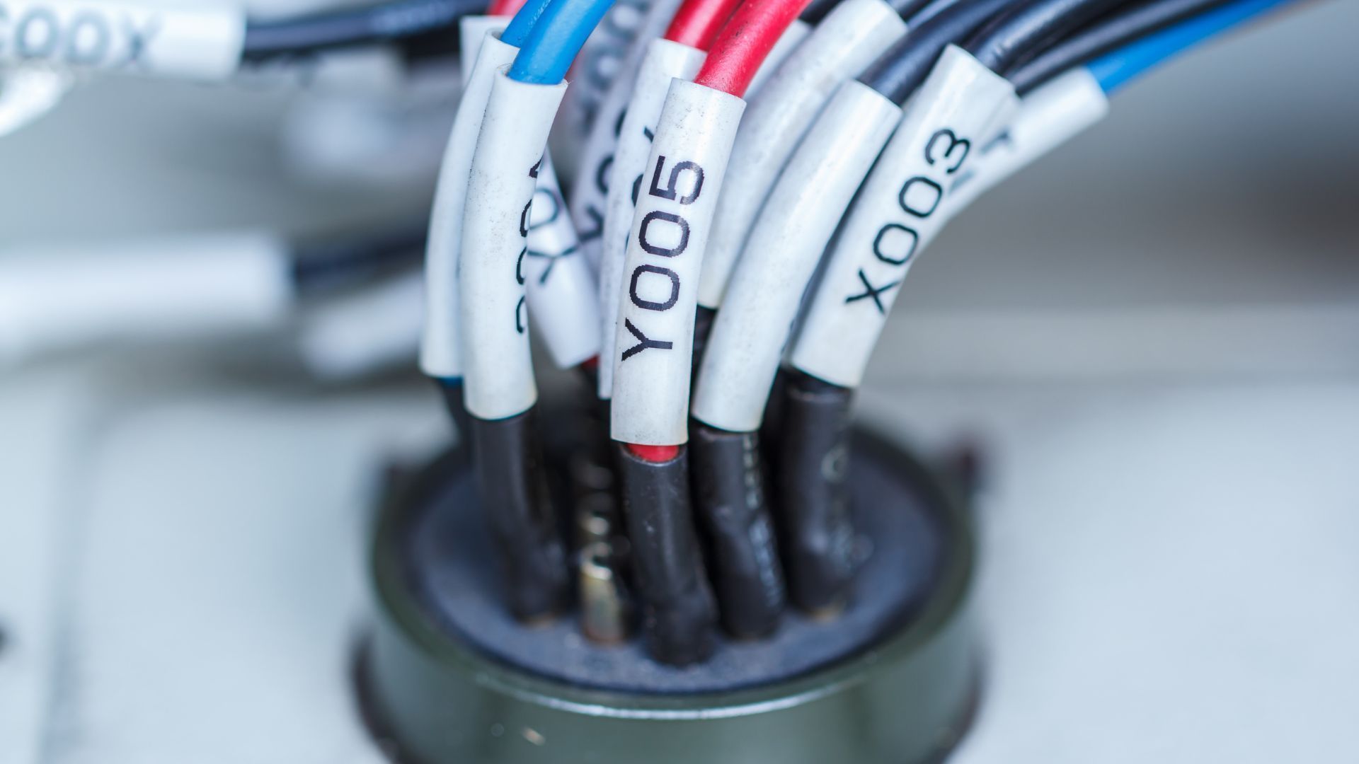 Close-up of labeled electrical wires entering a black cable grommet
