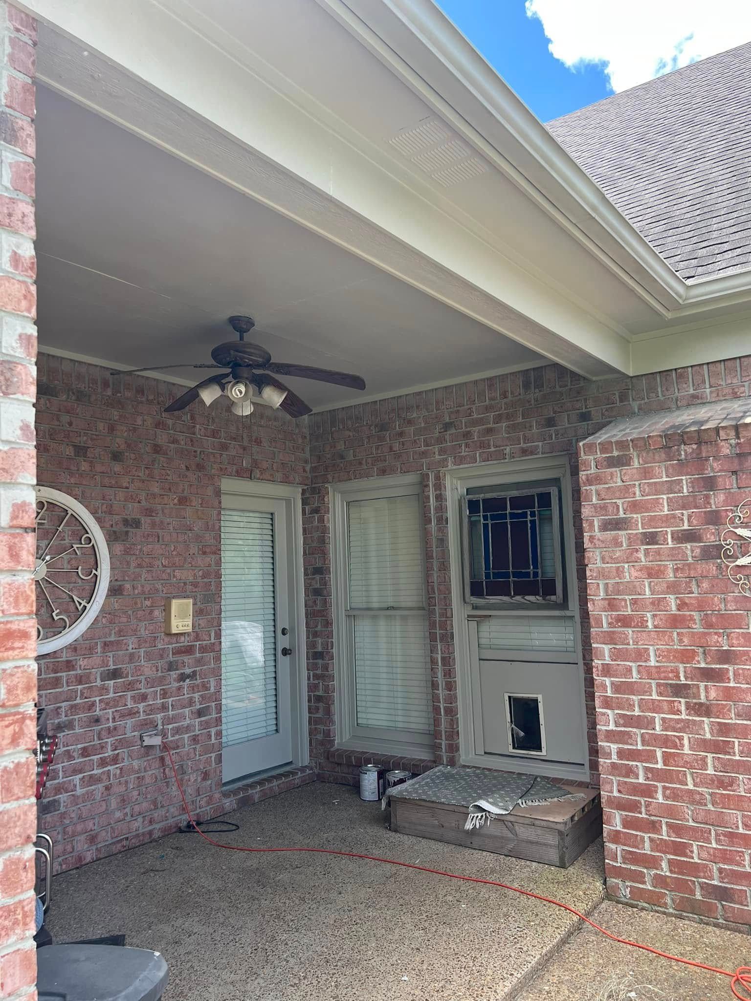 Brick-covered front porch with ceiling fan, screened door, windows, and a small bench under a covered roof