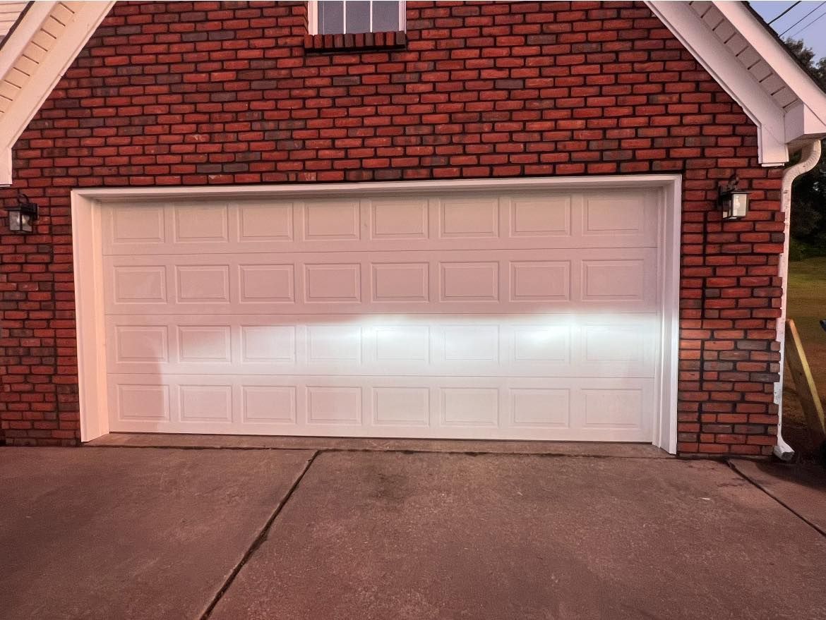 White garage door on a red brick house with driveway in front.