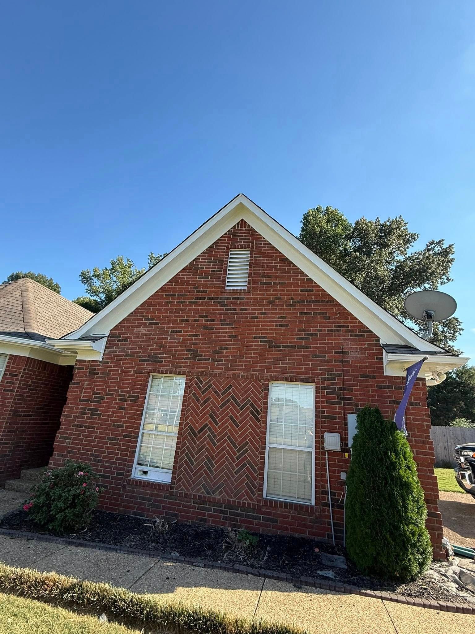 Red brick house exterior with boarded windows, white trim, and a small porch under a blue sky