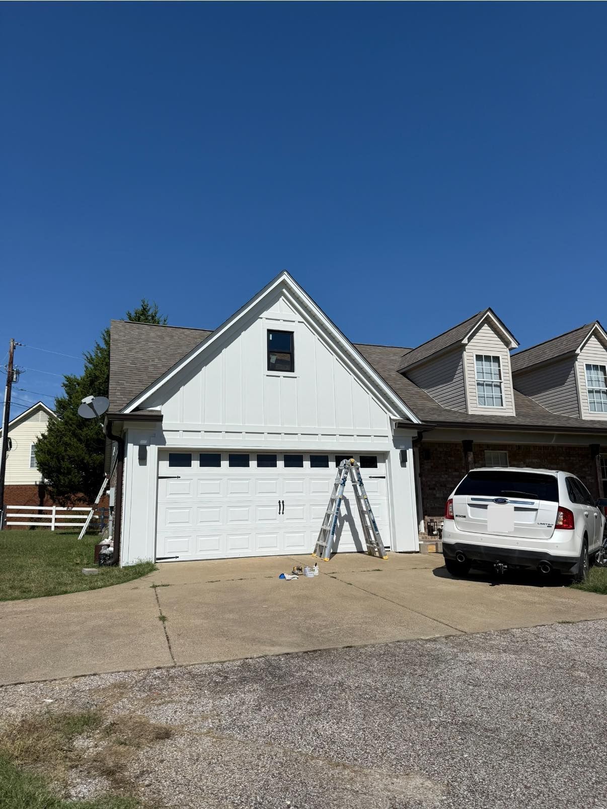 White garage and house exterior with parked SUV under a clear blue sky