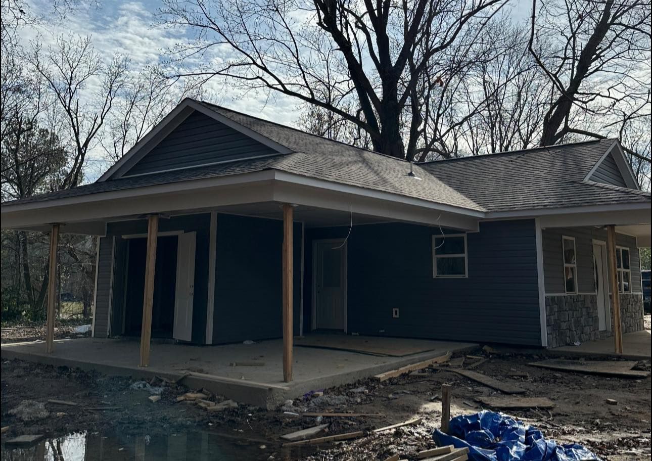Damaged blue house with boarded windows and a charred front yard after a fire