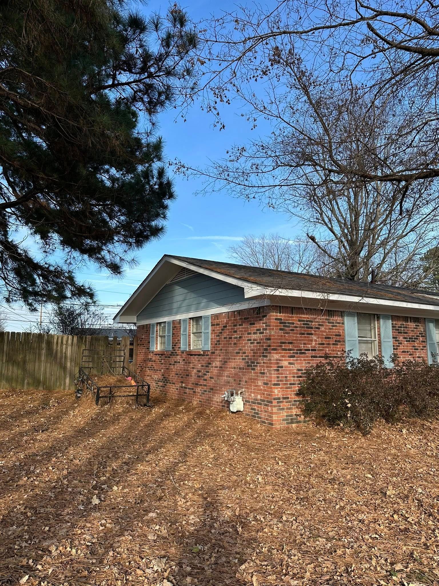 Brick house with blue trim on a wooded slope under a clear blue sky