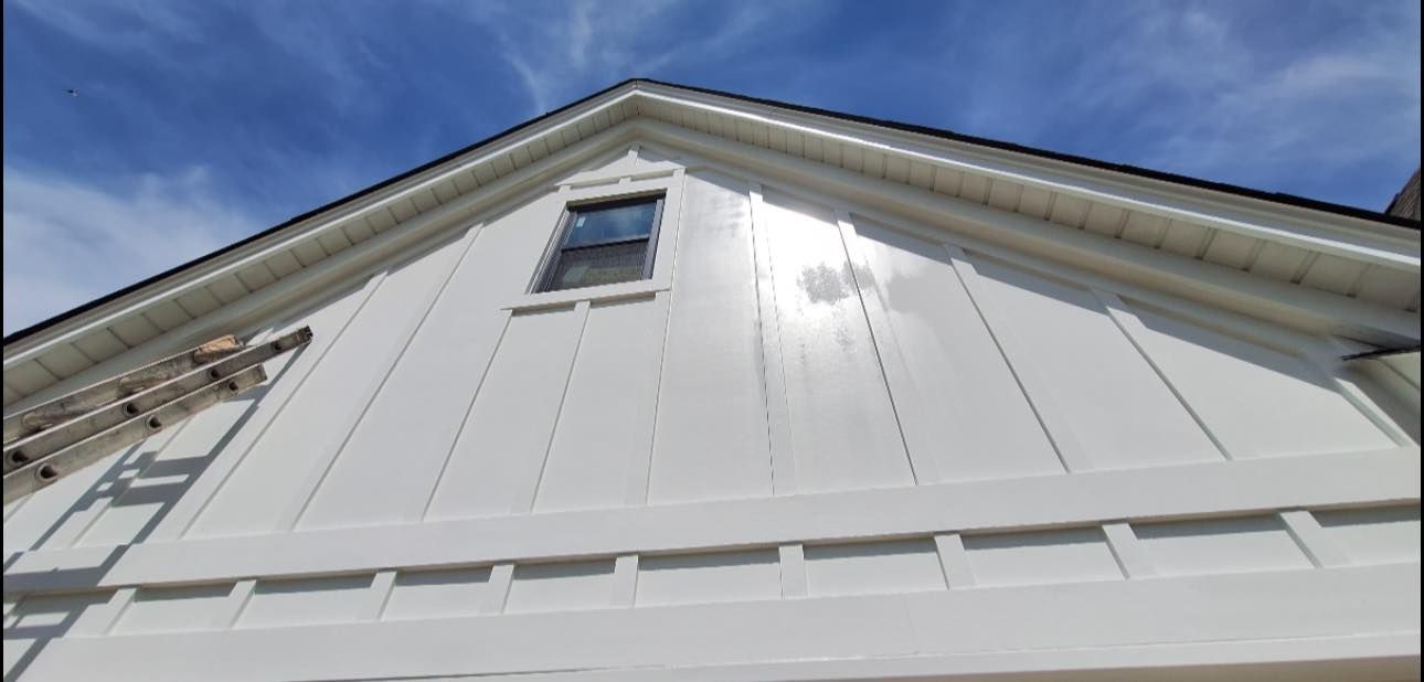 White house exterior with gable roof and a single small window against a blue sky