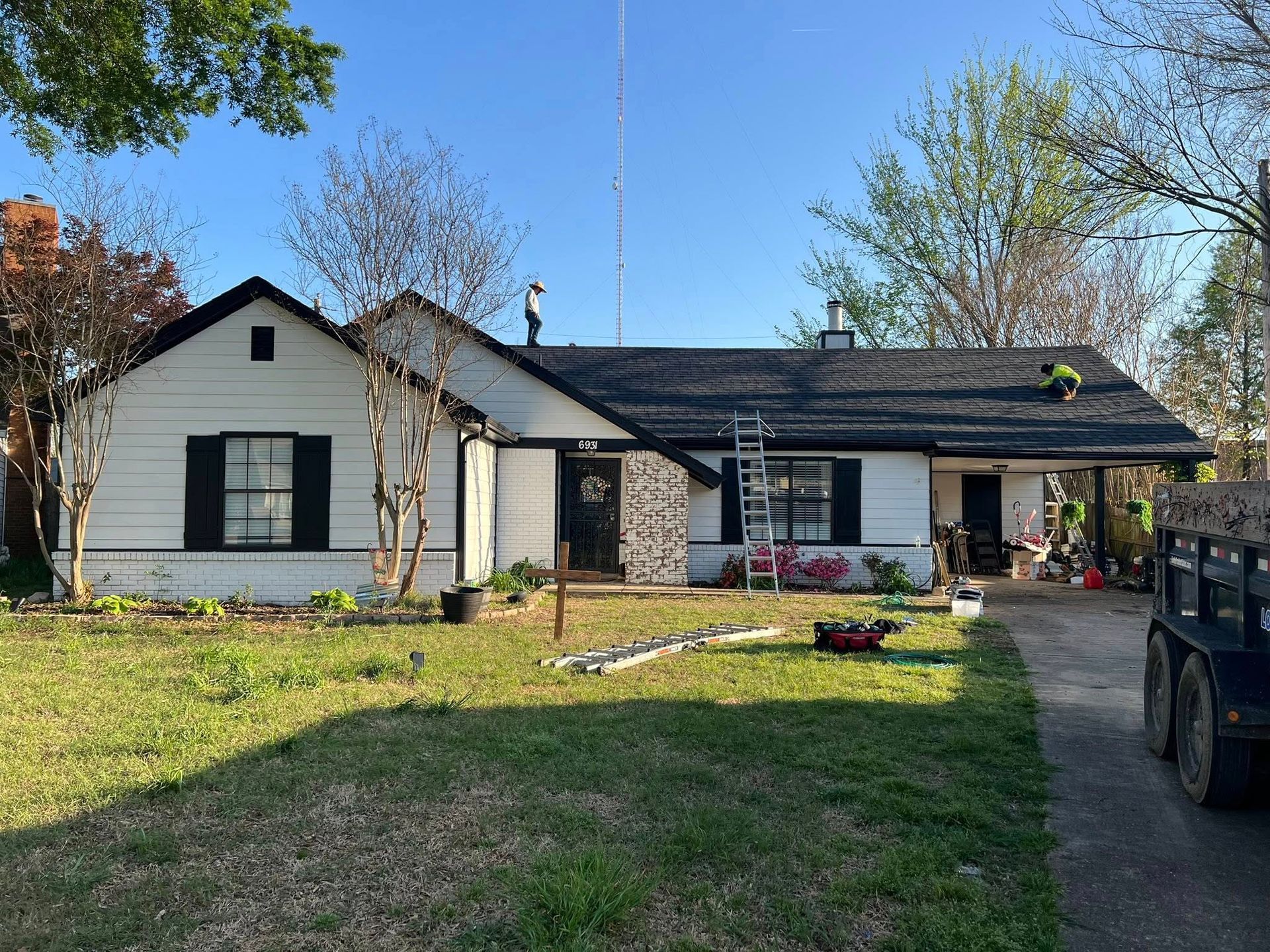 Single-story white house with black shutters and a front lawn under a clear sky