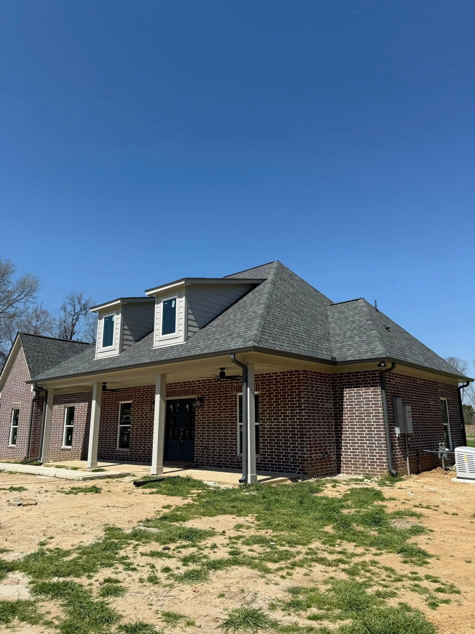 Brick house with gray roof and dormer windows on a sunny day