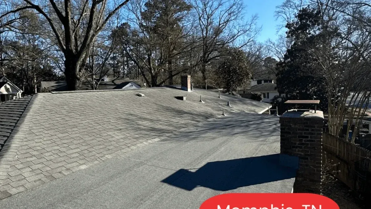 Rooftop with gray shingles and dormer vents under a clear blue sky, trees in the background