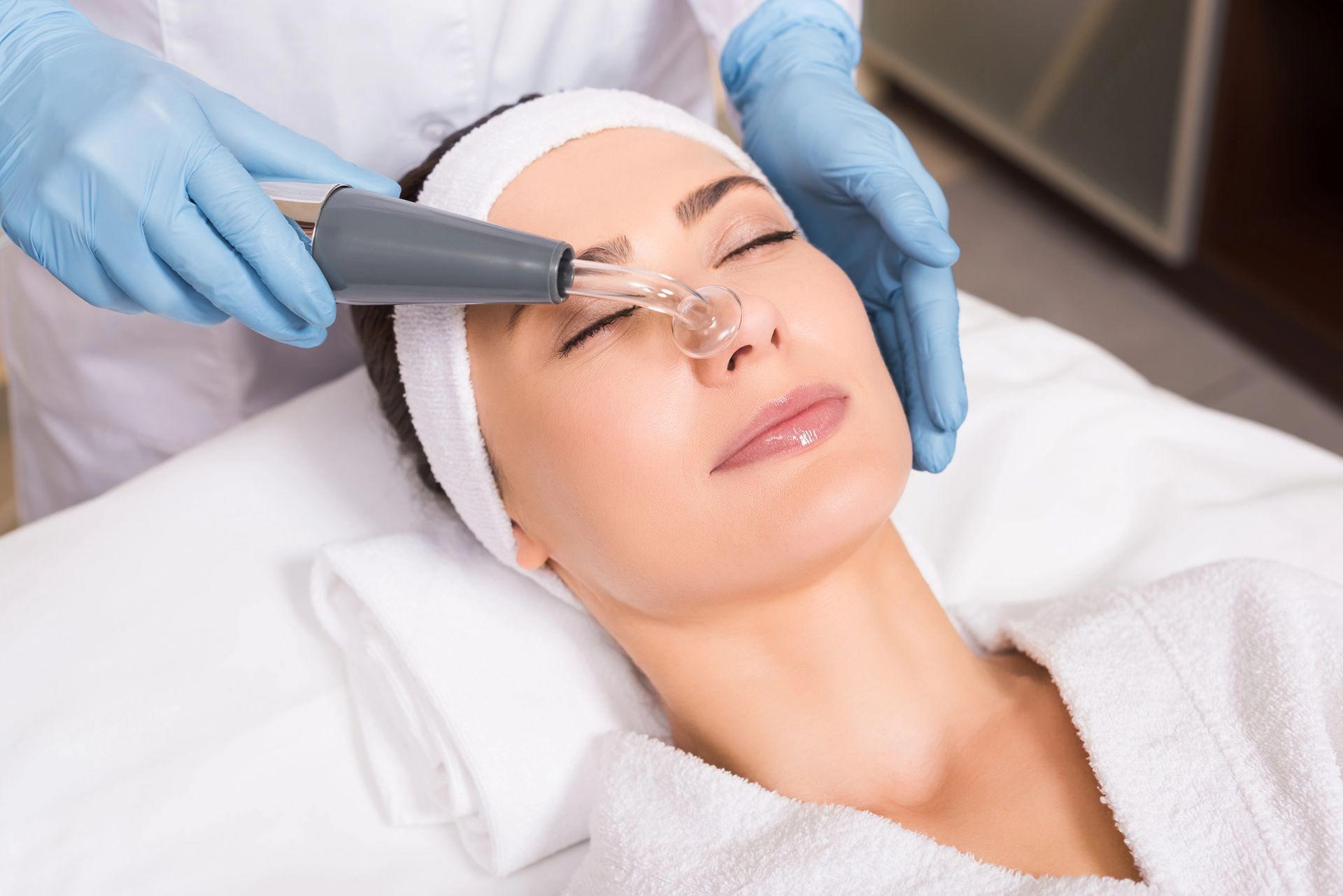 Trattamento estetico del viso con un dispositivo portatile sul viso di una donna in un ambiente spa.