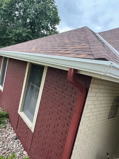 A red and white brick house with a brown roof. Big T Construction Roof Insurance Claim Approval.