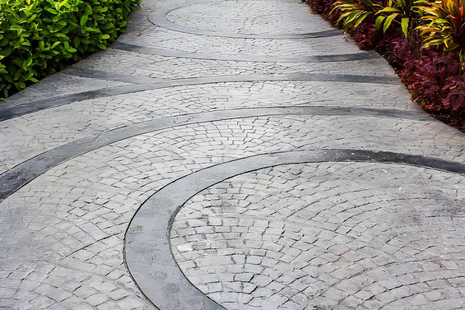 Curved stone pathway with gray pavers and green and burgundy garden borders