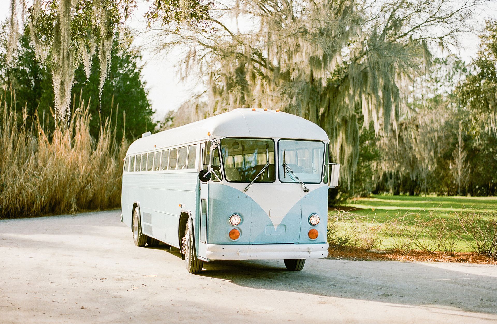 A blue and white bus is parked on the side of a road.