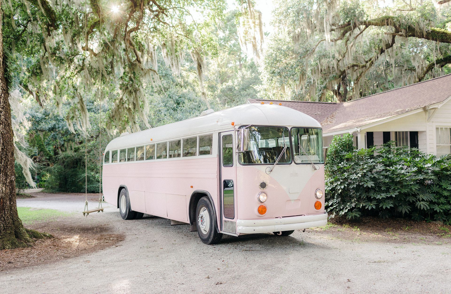 A pink school bus is parked in front of a house.