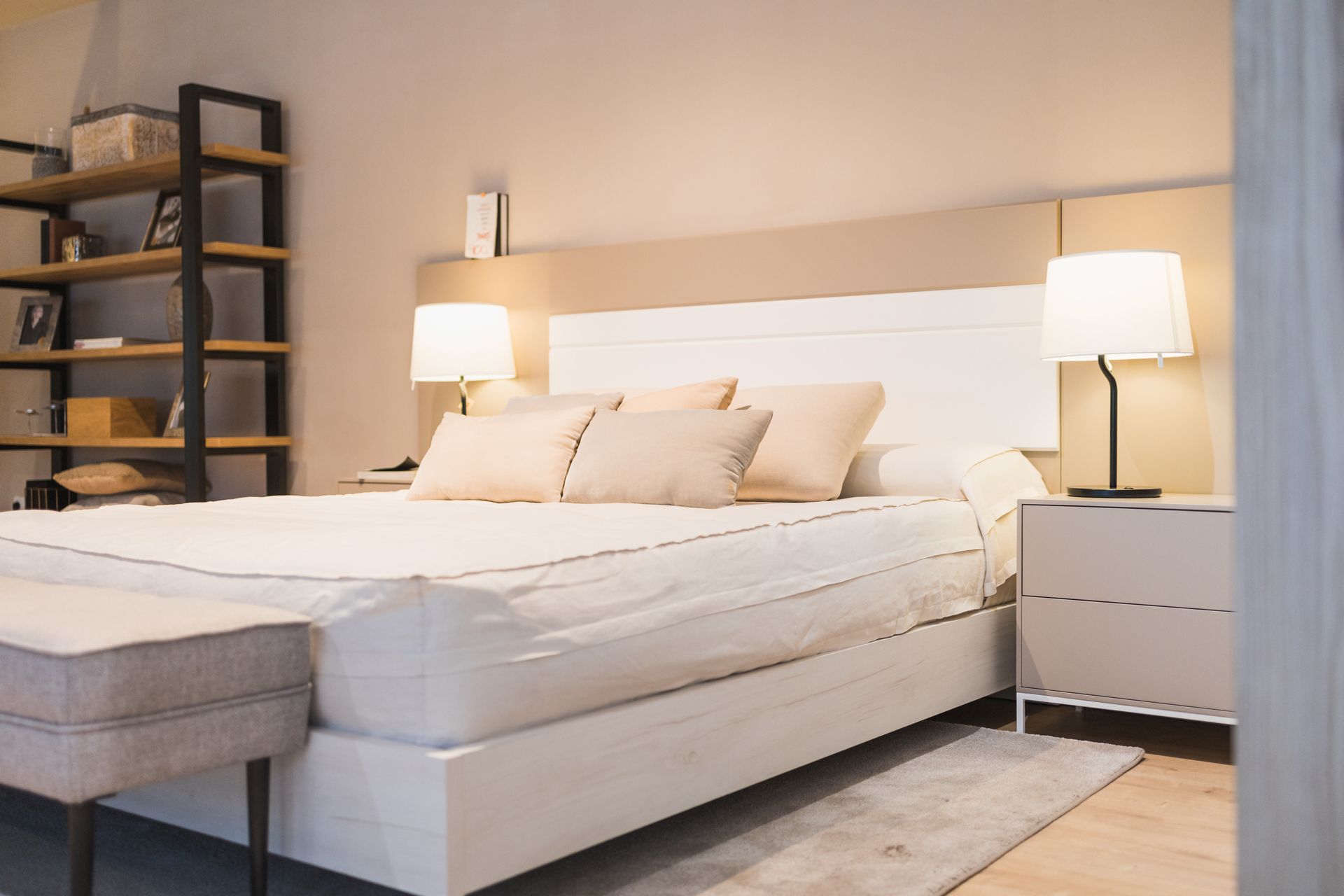 Photograph of a modern bedroom featuring a large white bed.