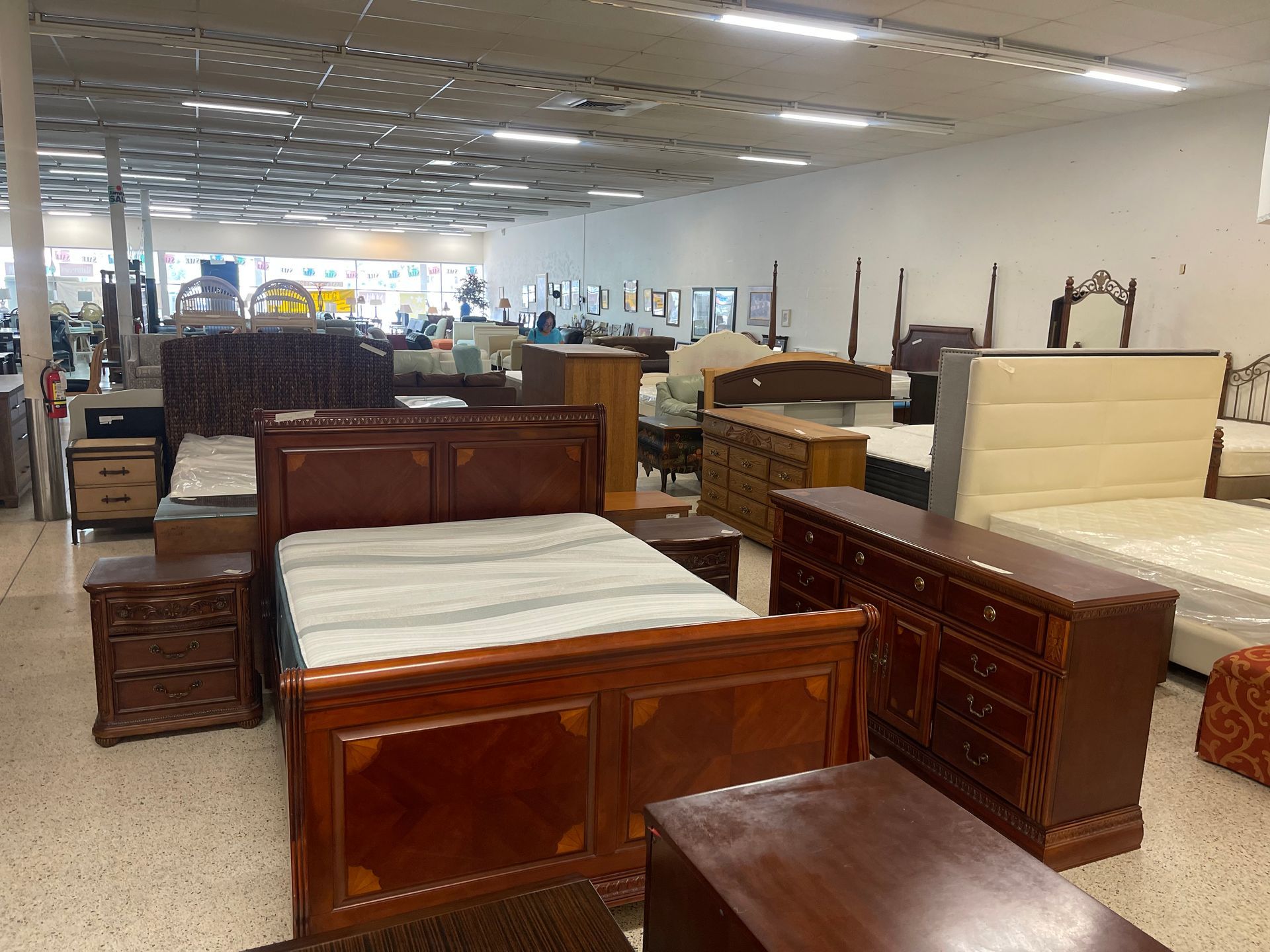 A showroom floor featuring several wooden bedroom sets, including beds, dressers, and nightstands.