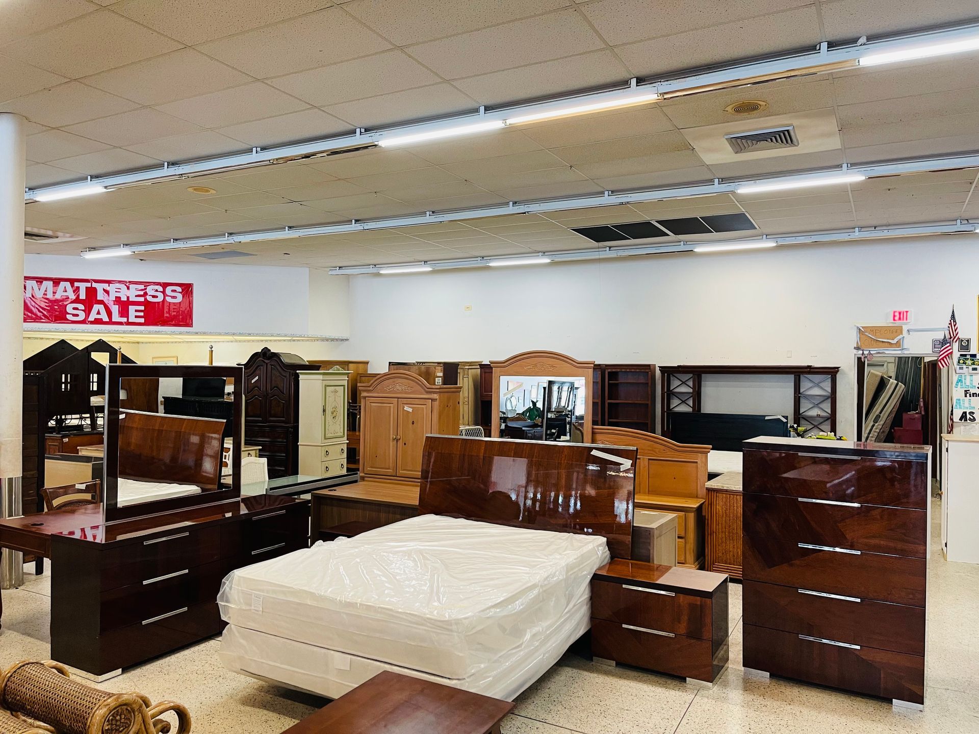A furniture store showroom displaying bedroom sets, including beds, dressers, and nightstands with a mattress sale sign.