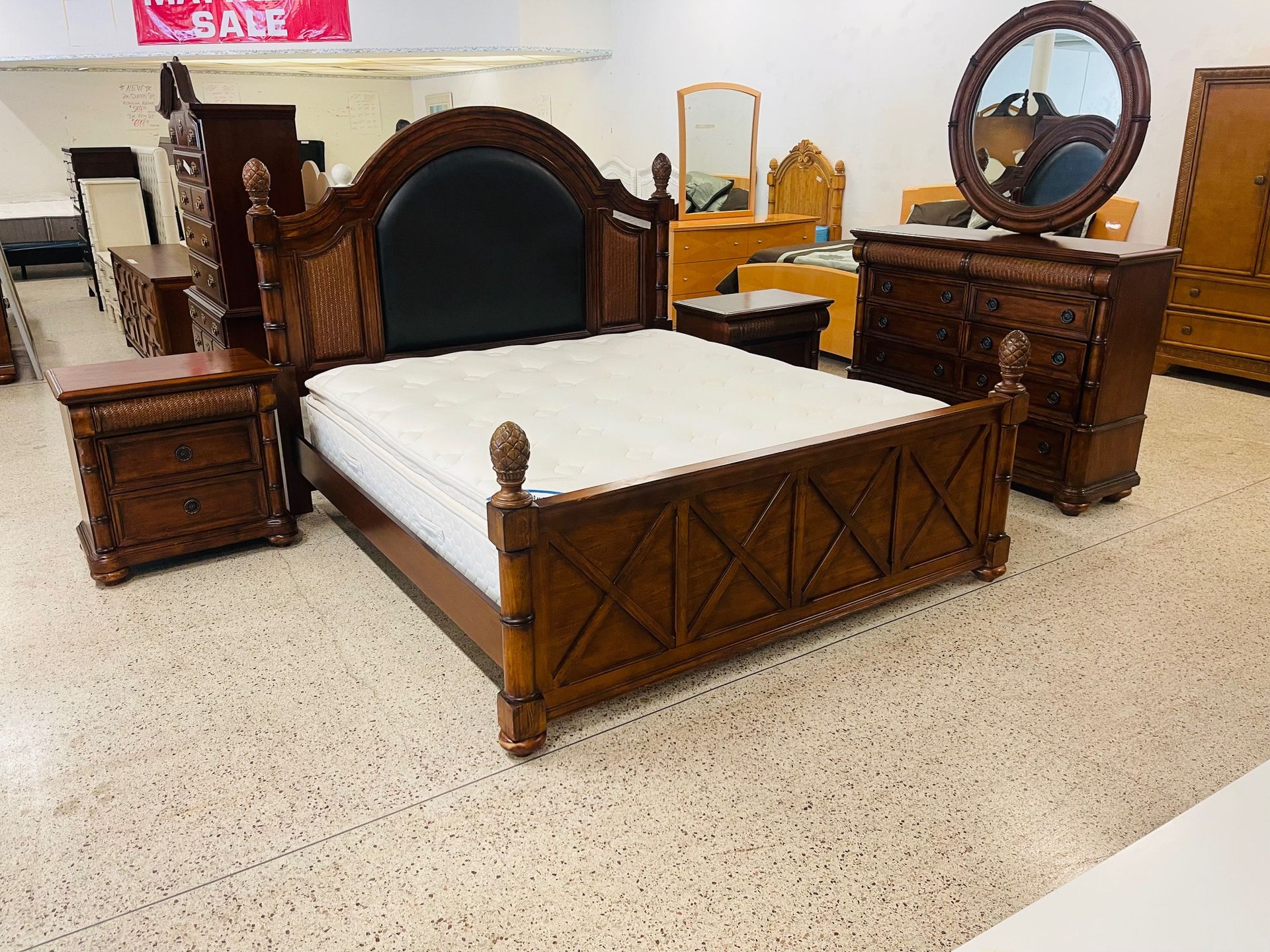 A bedroom furniture set featuring a dark wood bed with a black headboard, two nightstands, and a dresser with a mirror.