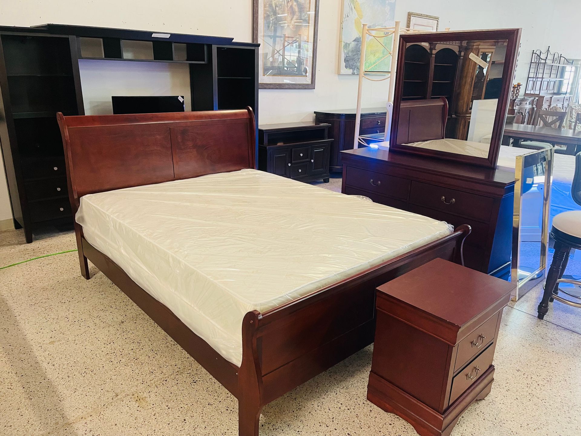 A dark wood bedroom set featuring a bed with a white mattress, a matching dresser with a mirror, and a nightstand.