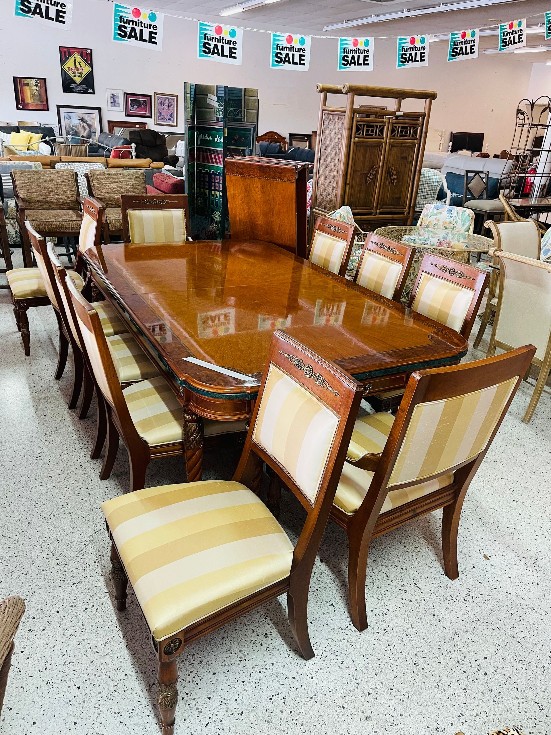 A formal wooden dining set with upholstered chairs on display in a retail store under 