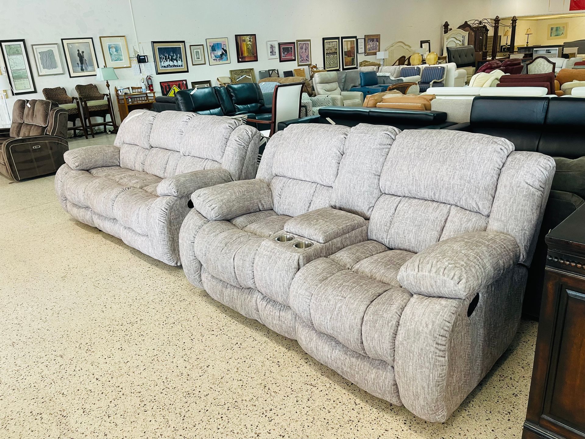 Two light-gray patterned reclining sofas in a brightly lit furniture showroom.