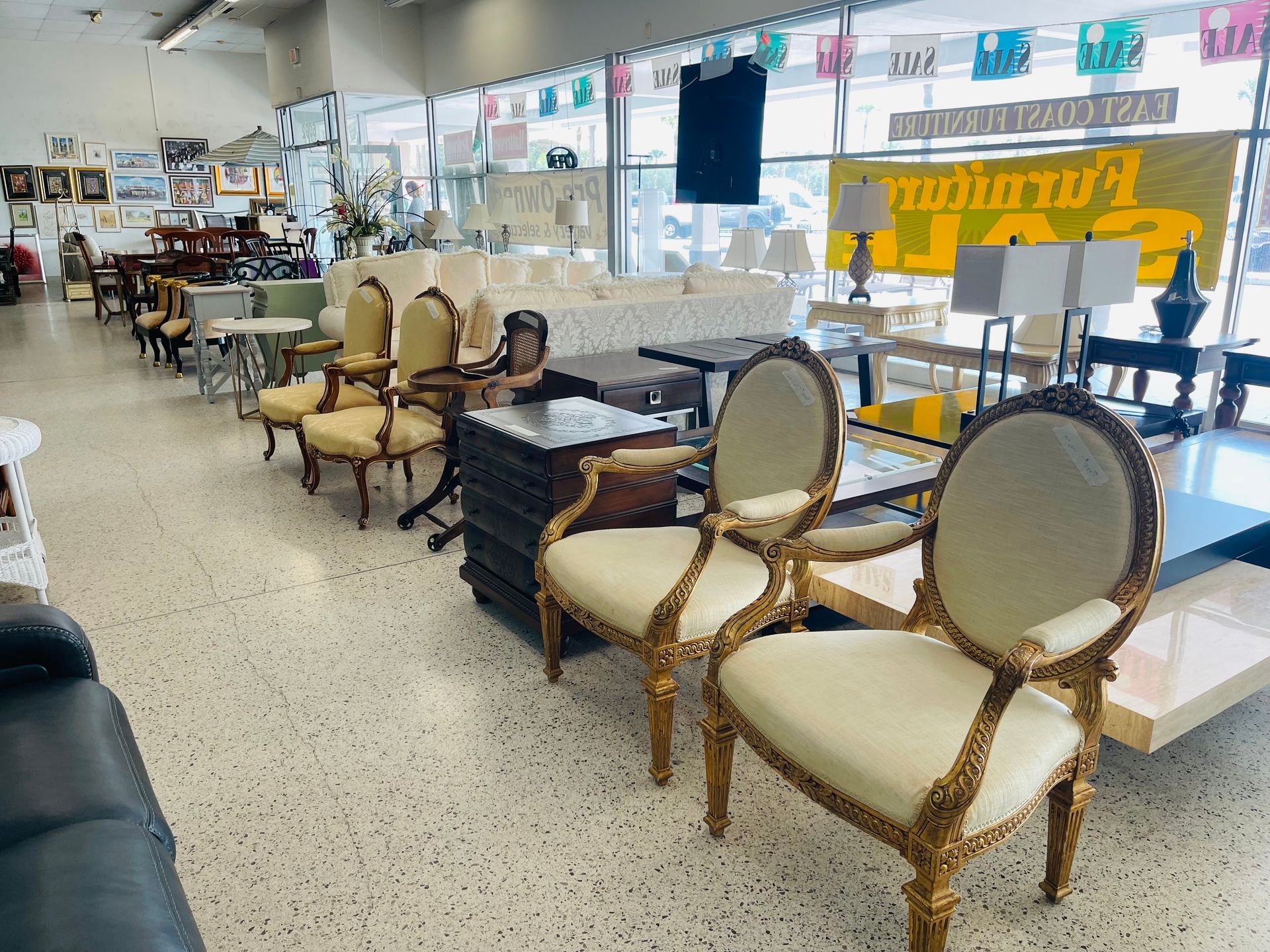 A retail furniture store interior with ornate, cream-colored chairs, sofa displays, and a large 