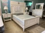 A bedroom with a bed , nightstand , mirror and dresser.