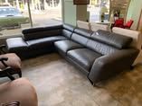 A gray leather sectional couch is sitting in a living room next to a window.