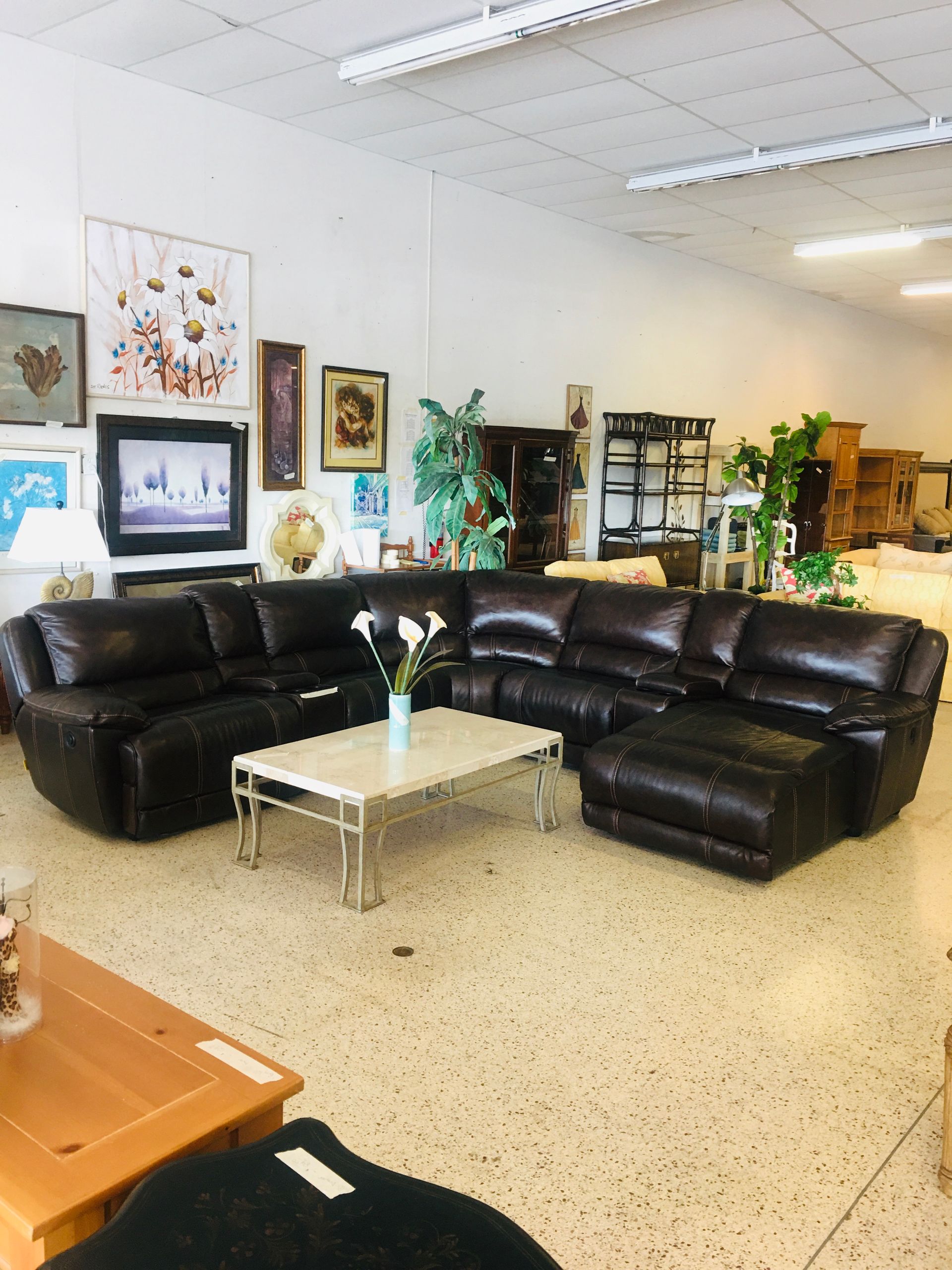 A dark brown leather sectional sofa with a white coffee table in a brightly lit furniture store showroom.