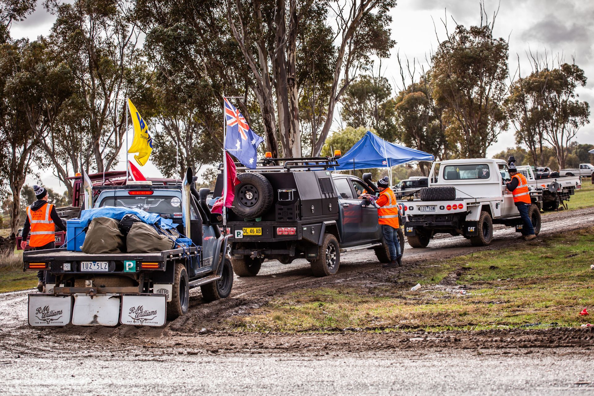 A group of off road vehicles are parked in a muddy field