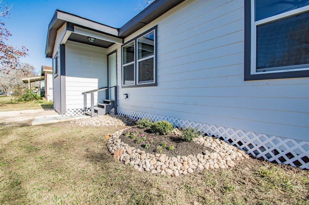 The front of a mobile home with a fence and a garden in front of it.